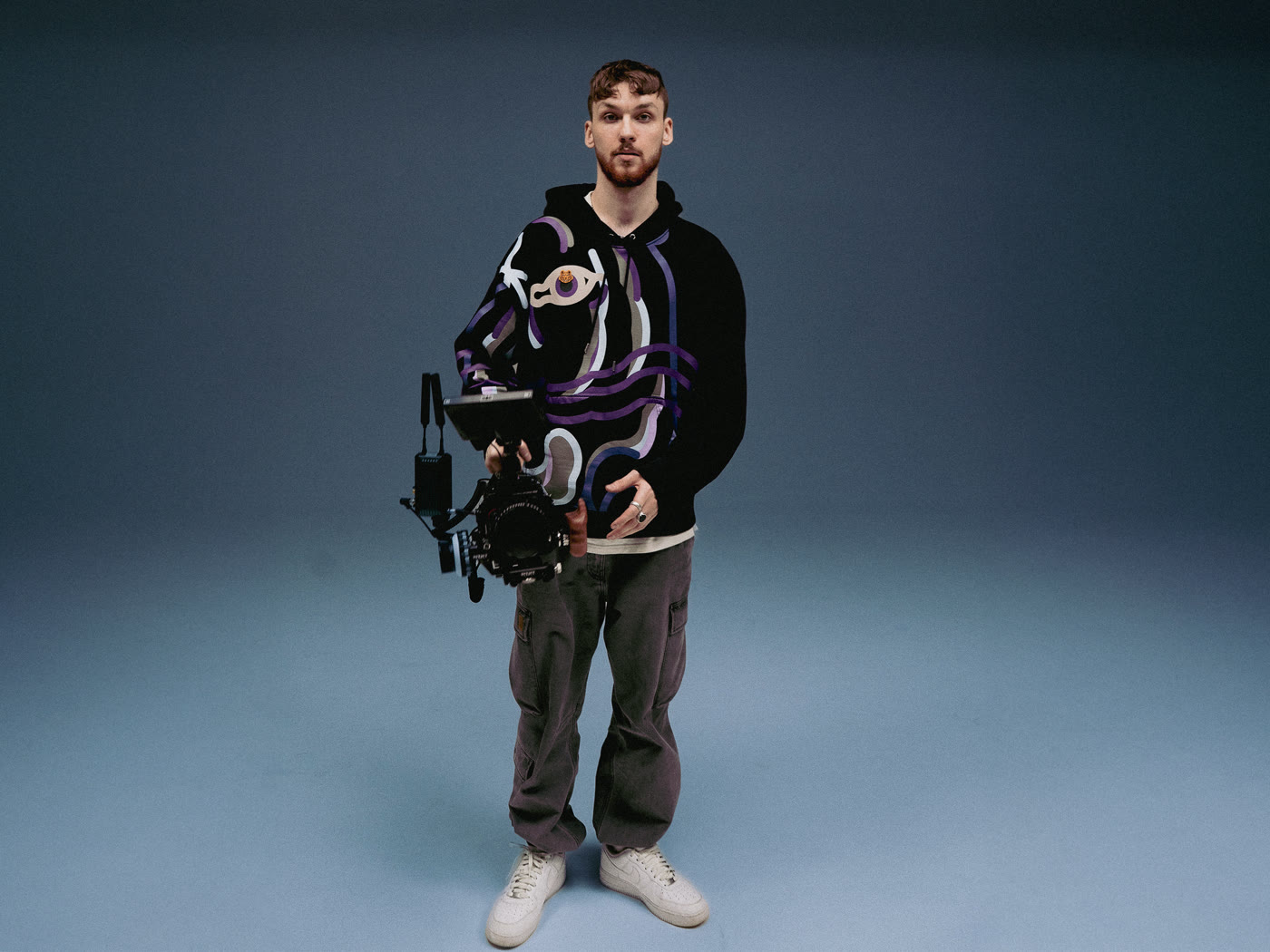 Pamir Shakir holding a cinema camera rig, studio portrait